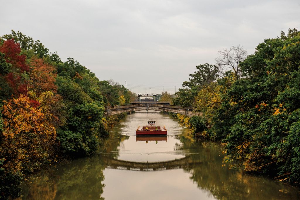a boat in a canal going under a walking bridge