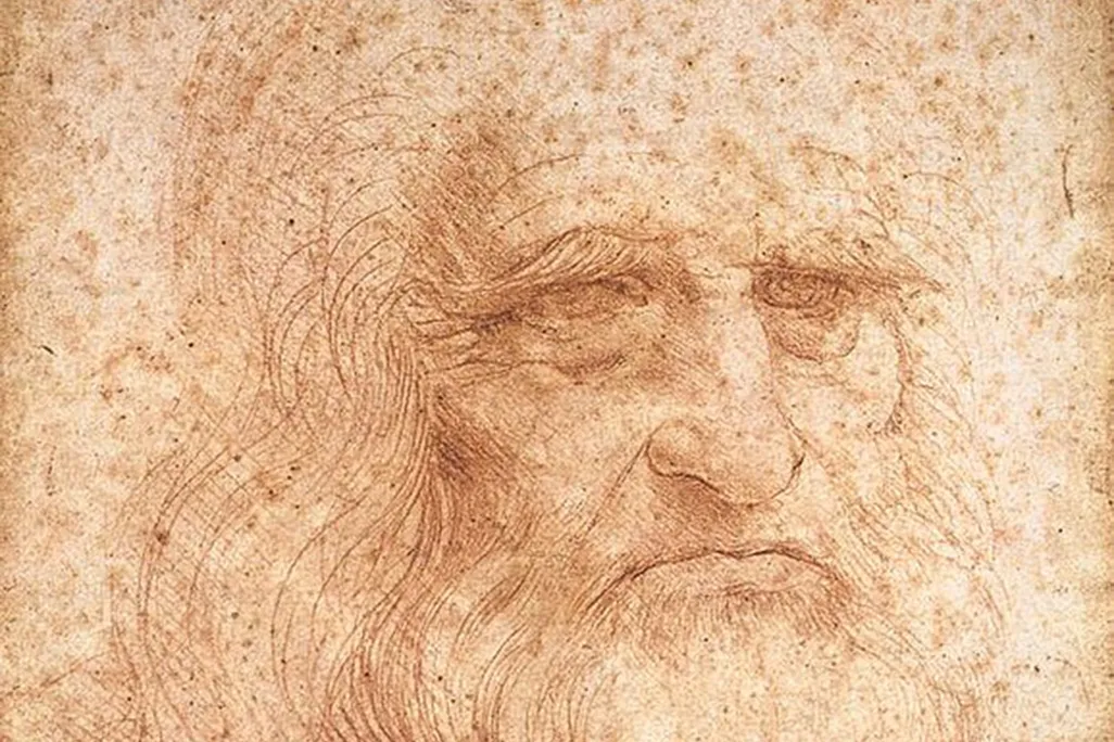 A portrait of an elderly man's face and long hair and beard, rendered in fine red chalk lines on a paper spotted with age