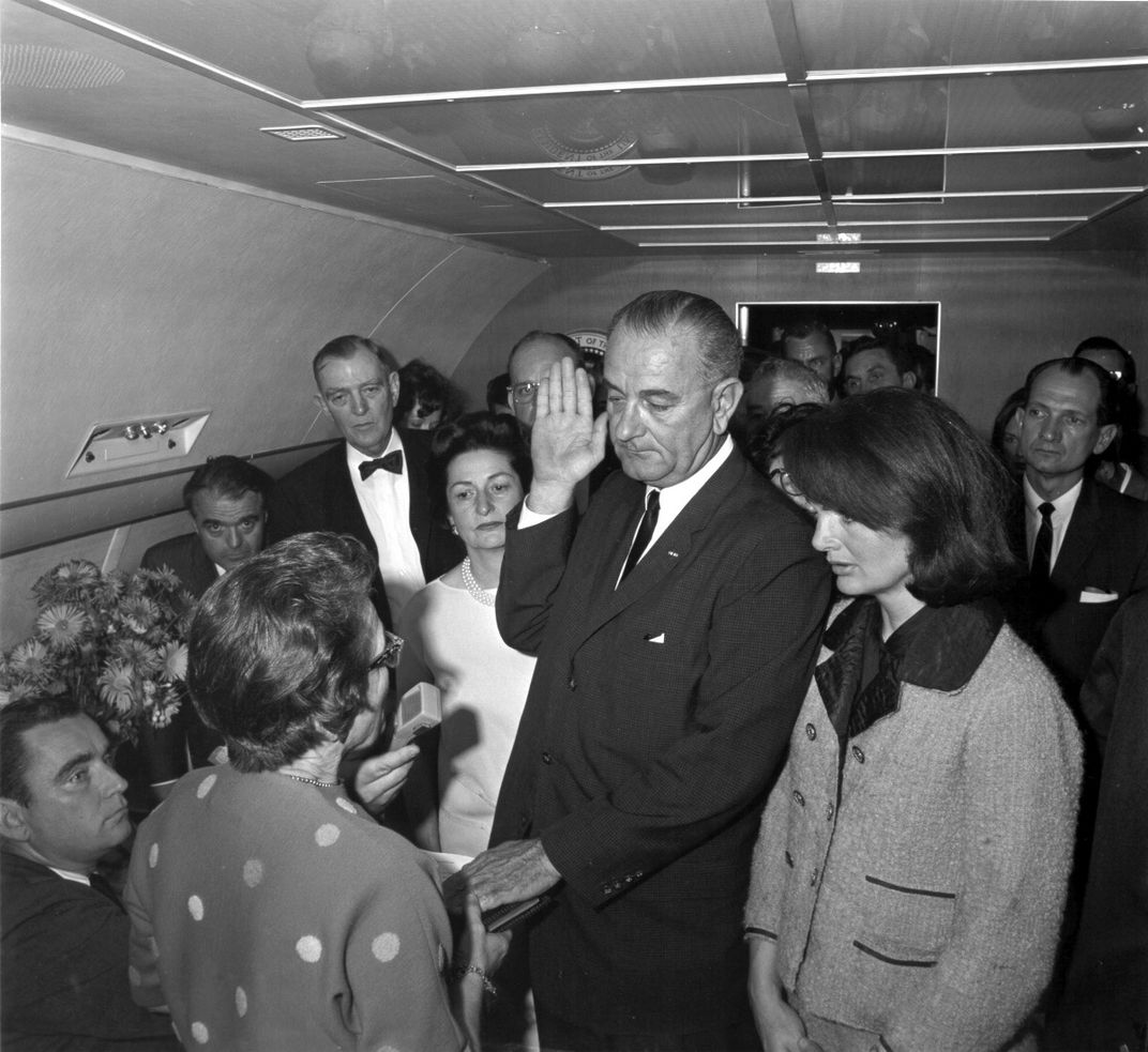 Lyndon B. Johnson, with Jackie by his side, takes the oath of office following Kennedy's assassination.