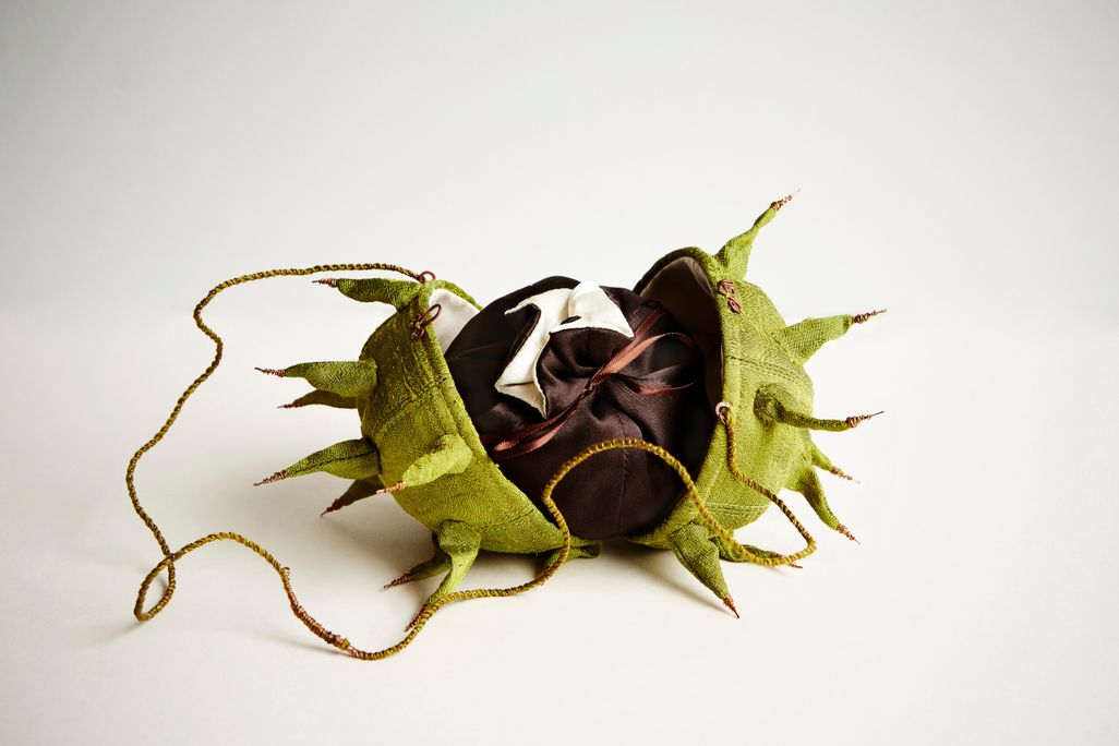 A purse designed to look the like green, spiked outside of a horse chesnut; displayed here, it opens into a small pouch