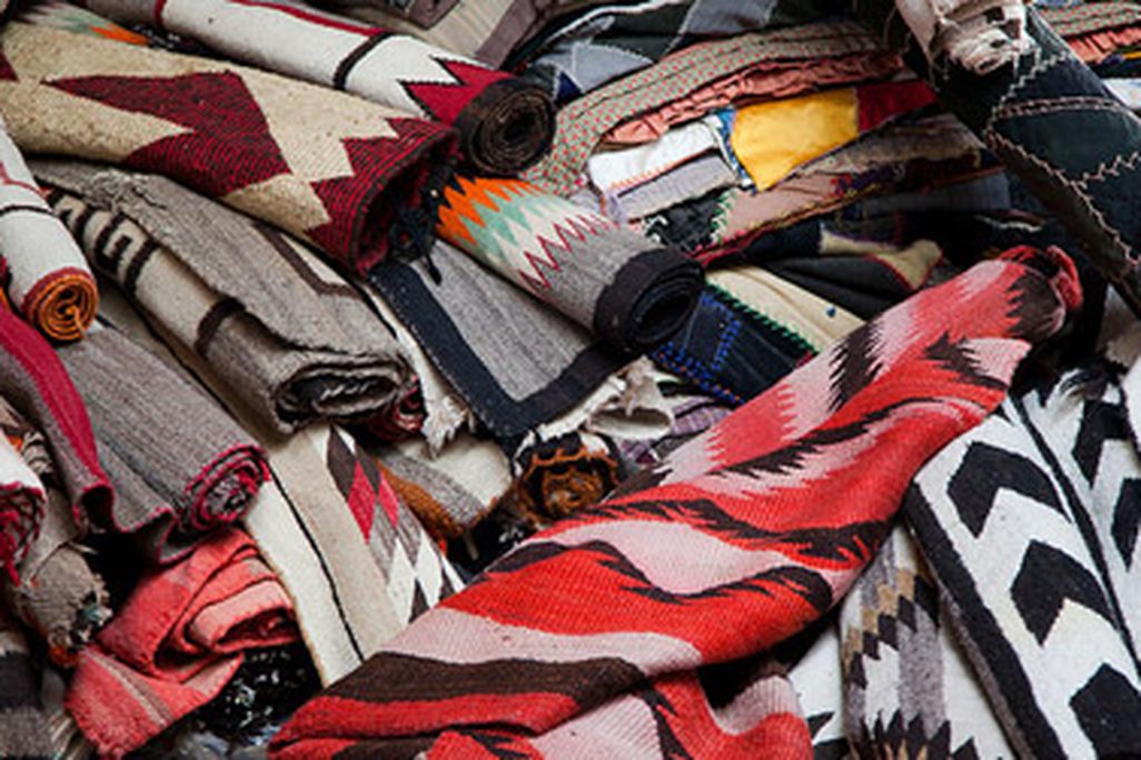 A potential buyer must carefully inspect the rugs at the Navajo rug auction