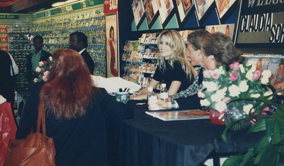 Claudia Schiffer sitting at a table