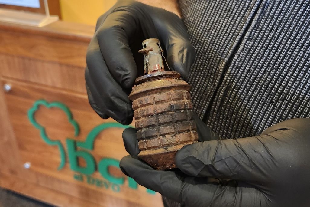 A pair of hands wearing black gloves holding a grenade