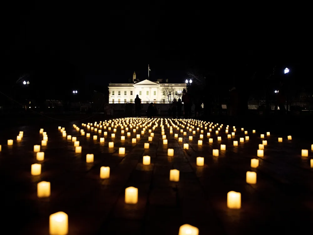 Electric candles on a lawn at night with the White House in the background