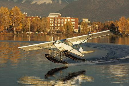 During a tranquil moment at Lake Hood, the world’s largest seaplane base, a Piper PA-14 skims a watery runway