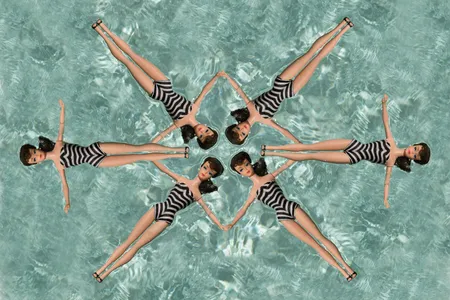 six Barbie dolls wearing zebra striped swimsuits in a synchronized formation in a swimming pool