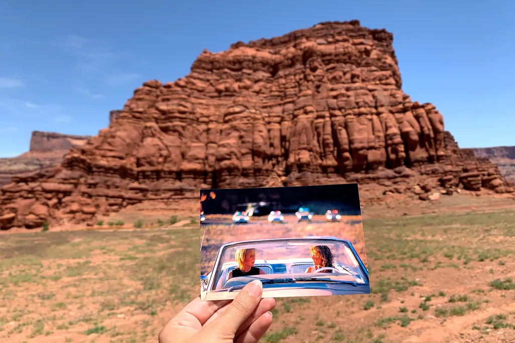 Person holding up a snapshot from the movie "Thelma & Louise" in front of rock formation