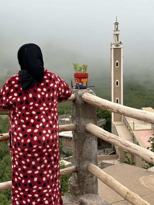 Woman viewing Atlas Mountain scene and mosque from her balcony. thumbnail