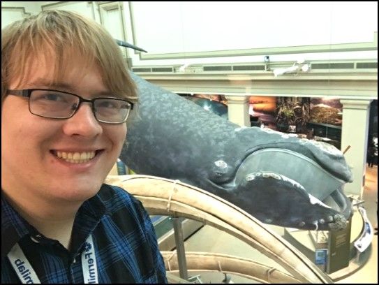 A visitor smiles for a selfie next to the North Atlantic right whale on display in the "Sant Ocean Hall" at the Smithsonian's National Museum of Natural History.