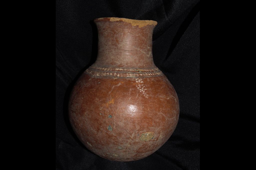 A reddish high-necked pot with some painting and visible cracks; mostly reddish-brown with specks of green and blue