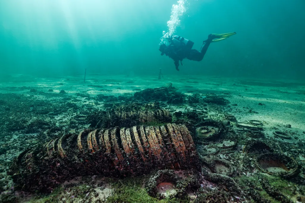 A diver swimming above a group of artifacts on a lake bed