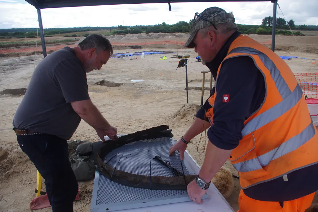 Two men looking down at artifact