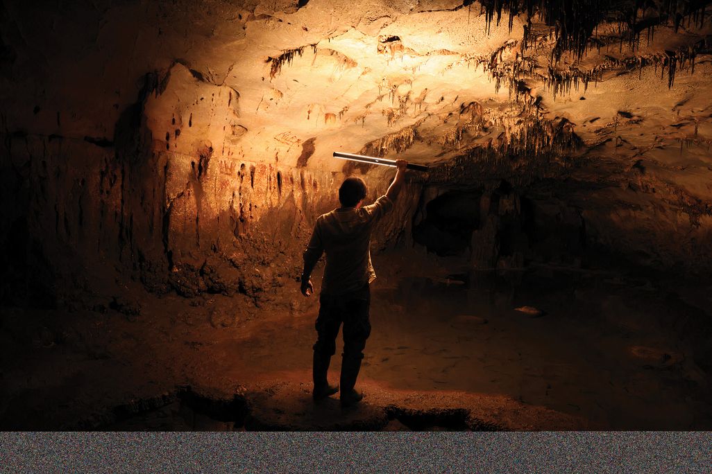 a man holding a flashlight inside a cave