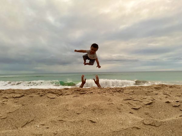 Baby boy goes airborne at the Pacific Ocean during sunset in Kauai. thumbnail