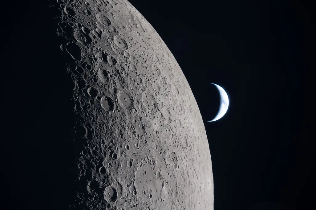 A crescent Earth floats beyond the moon on a dark background