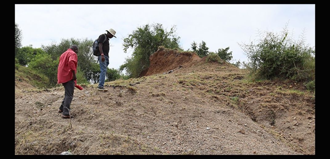 Two people climb a barren hill in Kenya