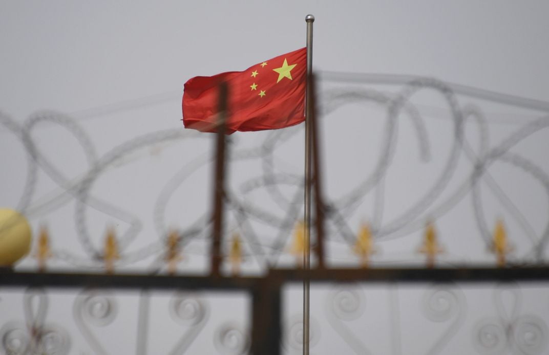 A June 4, 2019, photo of a Chinese flag behind razor wire at a housing compound in Yangisar, in China's western Xinjiang region.