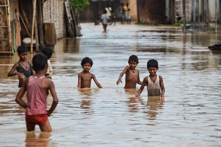 Children wade through flood waters in northern India in July 2013. 