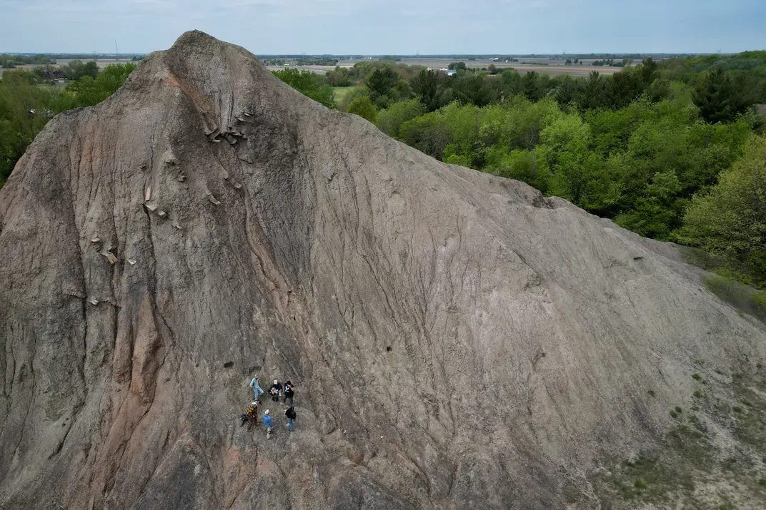 overhead view of a rocky peak with six people standing on the side, looking small