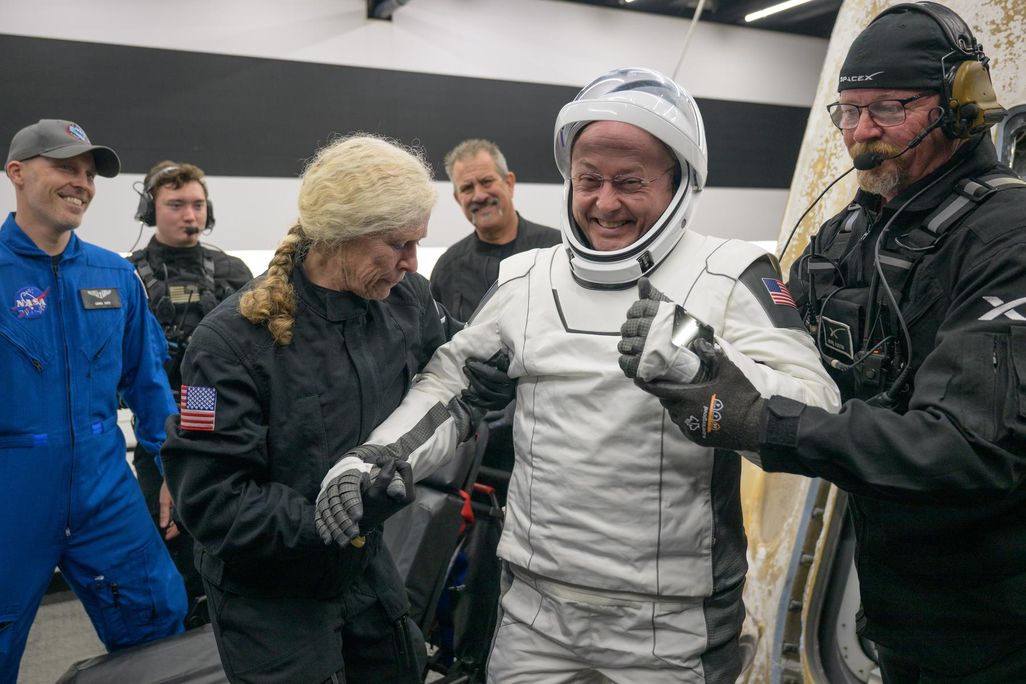 People helping a man in an astronaut suit