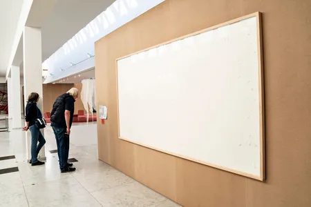 Visitors to the Kunsten Museum view Jens Haaning&#39;s Take the Money and Run&nbsp;(2021), consisting of two blank canvases.