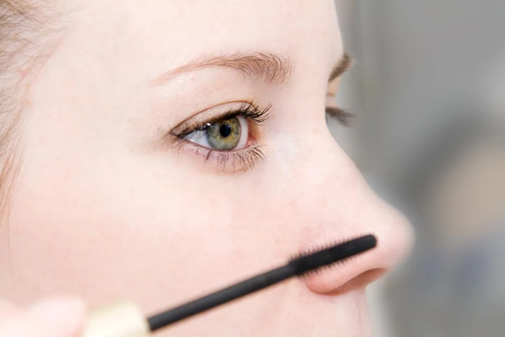 A woman applying mascara to her eyes