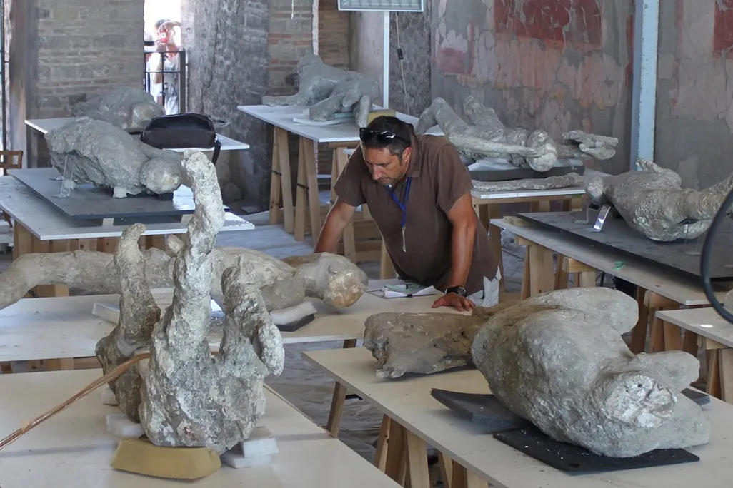 A man standing near plaster casts of human bodies
