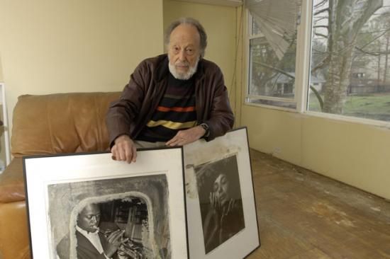 Man poses with two large black and white photo prints