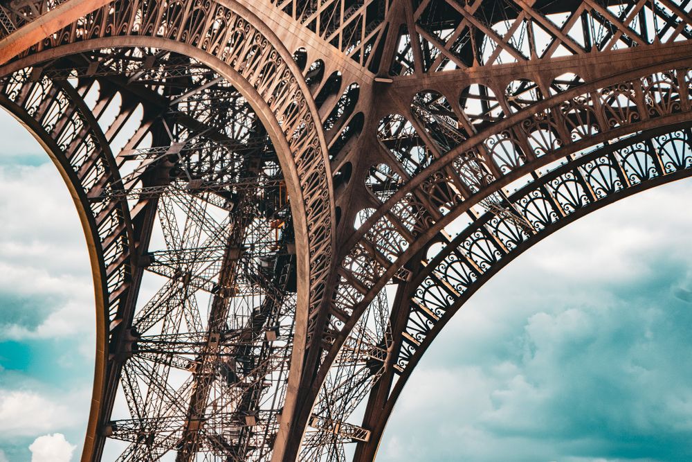 A close-up look at the iron arches of the Eiffel Tower in Paris, highlighting its patterns and structure.
