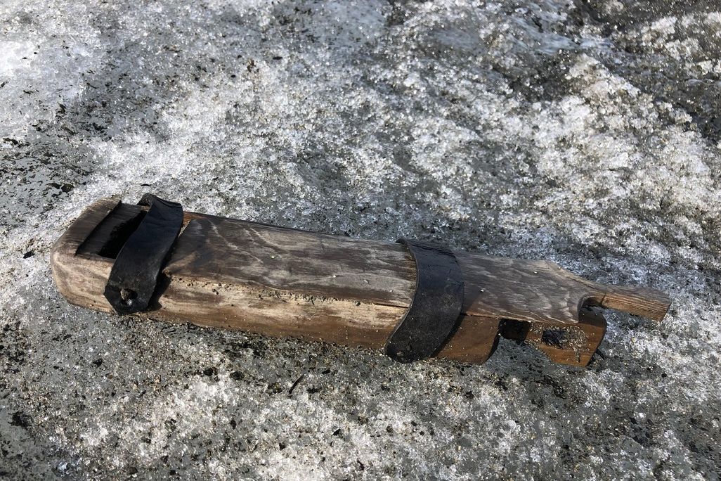 A long rectangular wooden box rests on a rocky surface outdoors