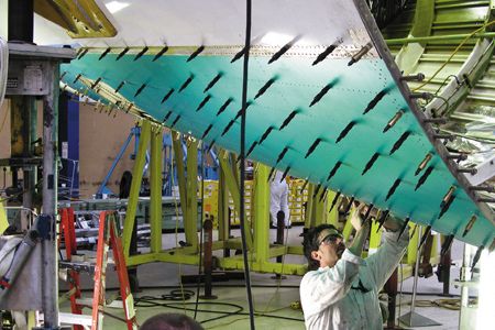 Fred Chadwick and Ron Beatty (foreground) install temporary fasterners that hold the skin in place for riveting.