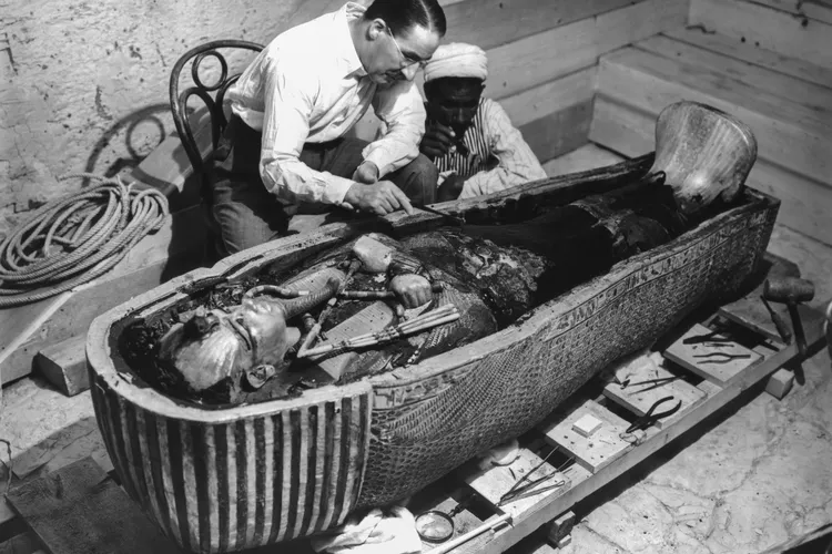 Howard Carter and an Egyptian man examining King Tut's sarcophagus