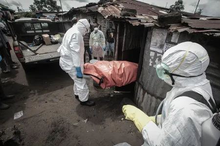 Garmai Sumo with the Liberian red cross supervises a burial team as they pull out the body of 40-year-old Mary Nyanforh, in Monrovia, Liberia, on October 14, 2014.