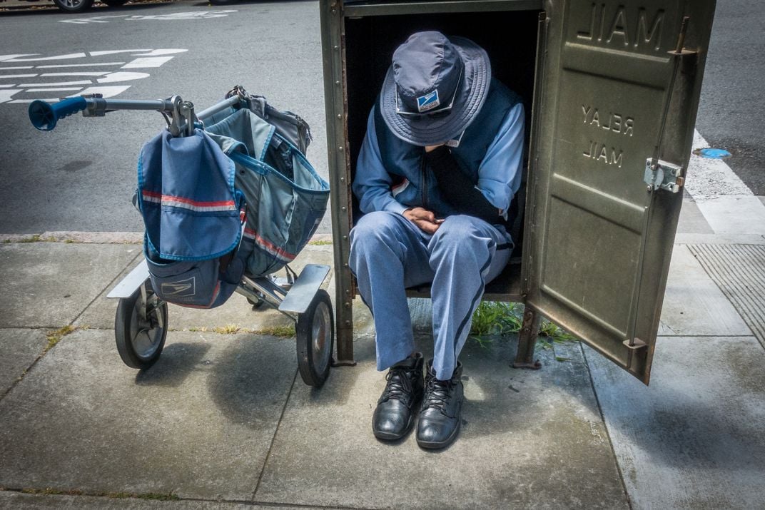A mailman sits inside a mailbox