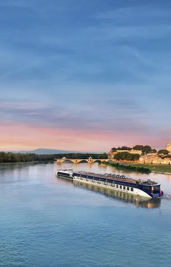 River Cruises - small cruise ship on a river in France at sunset.