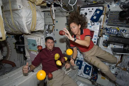 Astronauts Shane Kimbrough and Sandy Magnus play with floating food during the STS-126 shuttle mission.