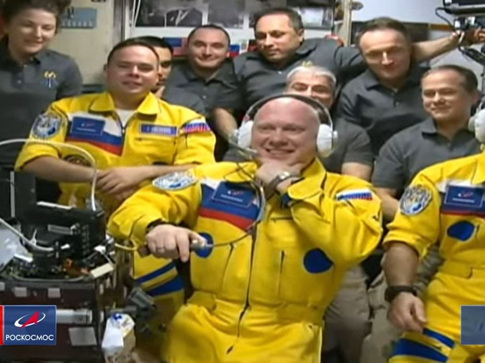 three russian astronauts inside the crowded international space agency after they arrive friday wearing yellow and blue coveralls