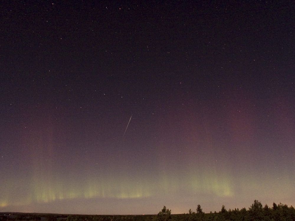 a draconid meteor streaks across the sky with the northern lights visible