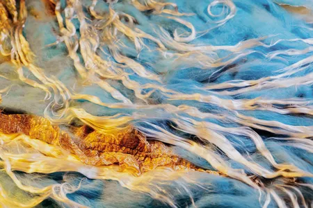Though stationary, fibers of different colors and textures are combined in ways that suggest water or air in motion and subject to the whims of turbulence.