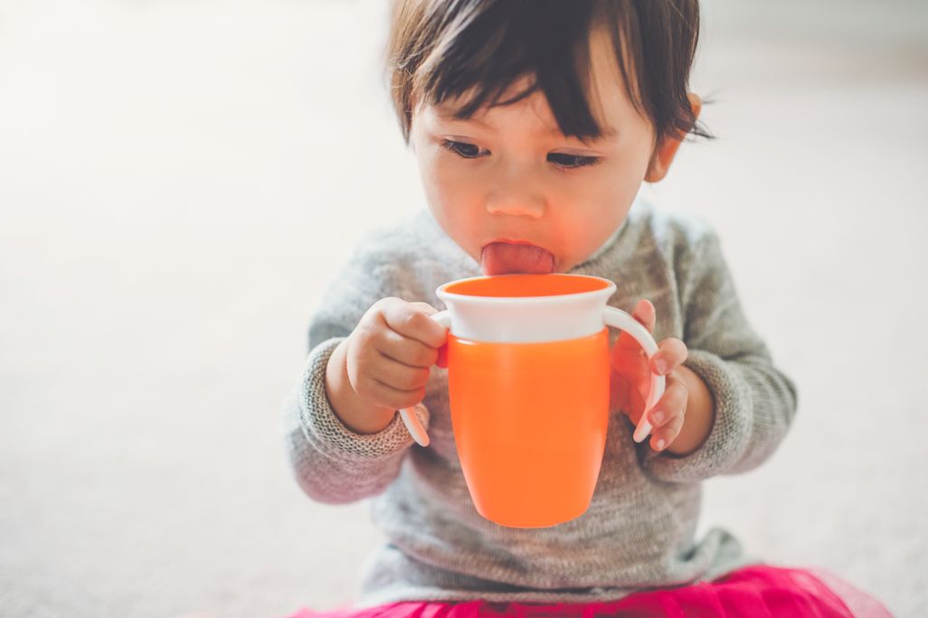 A child holding an orange sippy cup