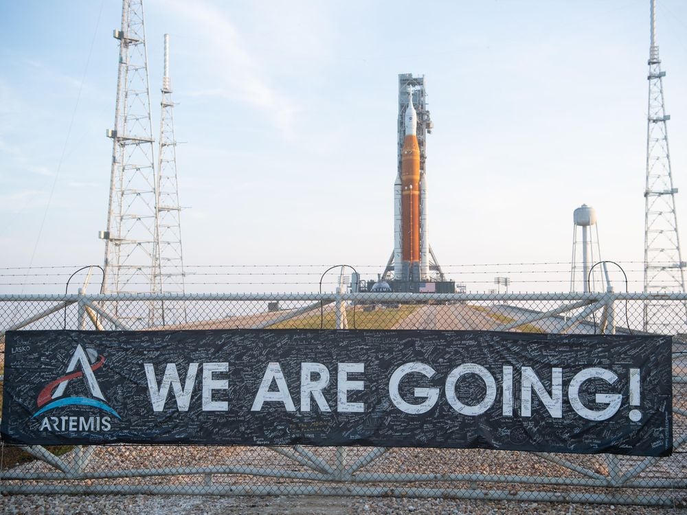 Banner on fence reads "We are going!" in front of the SLS rocket