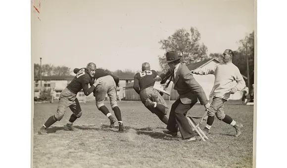 Photograph of John Steuart Curry sketching a football practice at the University of Wisconsin-Madison, 1936 or 1937 / unidentified photographer. John Steuart Curry and Curry family papers, 1848-1999. Archives of American Art, Smithsonian Institution.