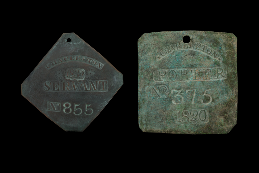 Two old metal badges next to each other against a black background