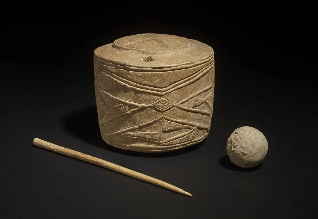 stone drum with carvings, bone pin and smooth clay ball