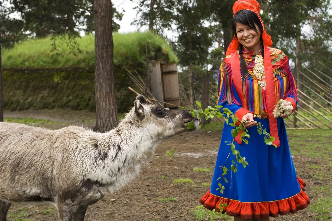 Woman in traditional Sami dress with reindeer. Credit: Norway Tourism Bureau