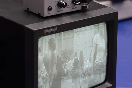 A small black and white tv monitor displays a fuzzy image on the screen. On top of it sits a box with nobs.
