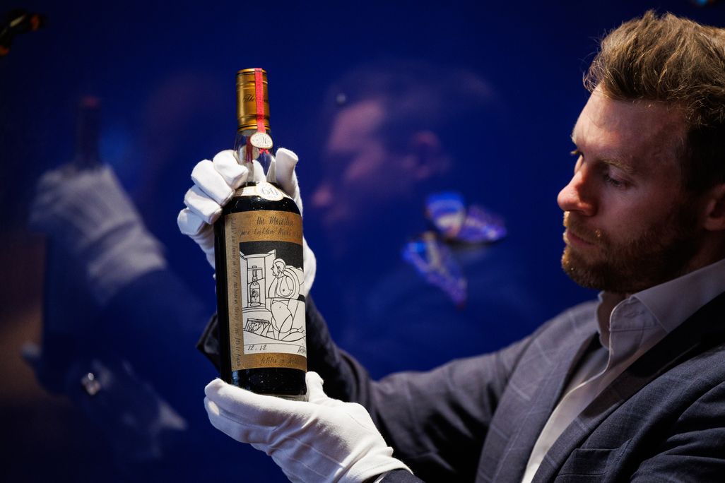 Man wearing white gloves posing with a bottle of whisky