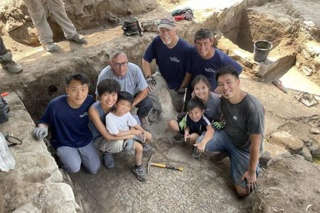 Archaeologists pose near the inscription found on the north shore of the Sea of Galilee