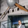 A white man in his late 30s stands inside a gallery displaying aviation artifacts, including a four-blade fan mounted on the wall.