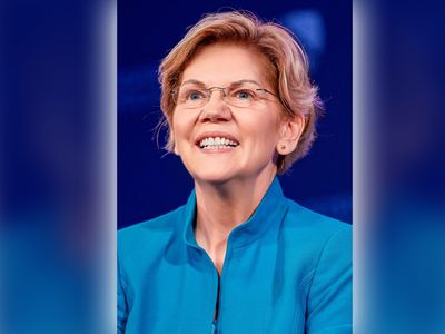 Image of a woman, Elizabeth Warren, smiling in a blue shirt